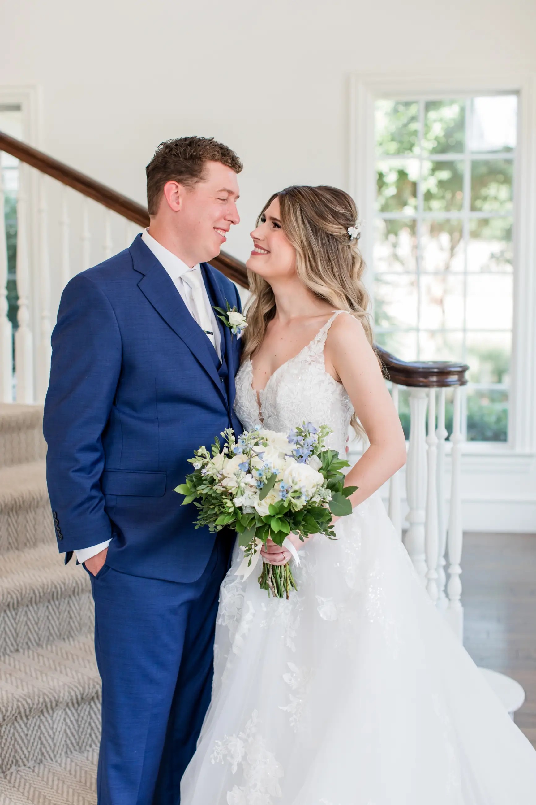 image shows a bride smiling at her husband on their wedding day, and she is wearing a sophia tolli wedding dress
