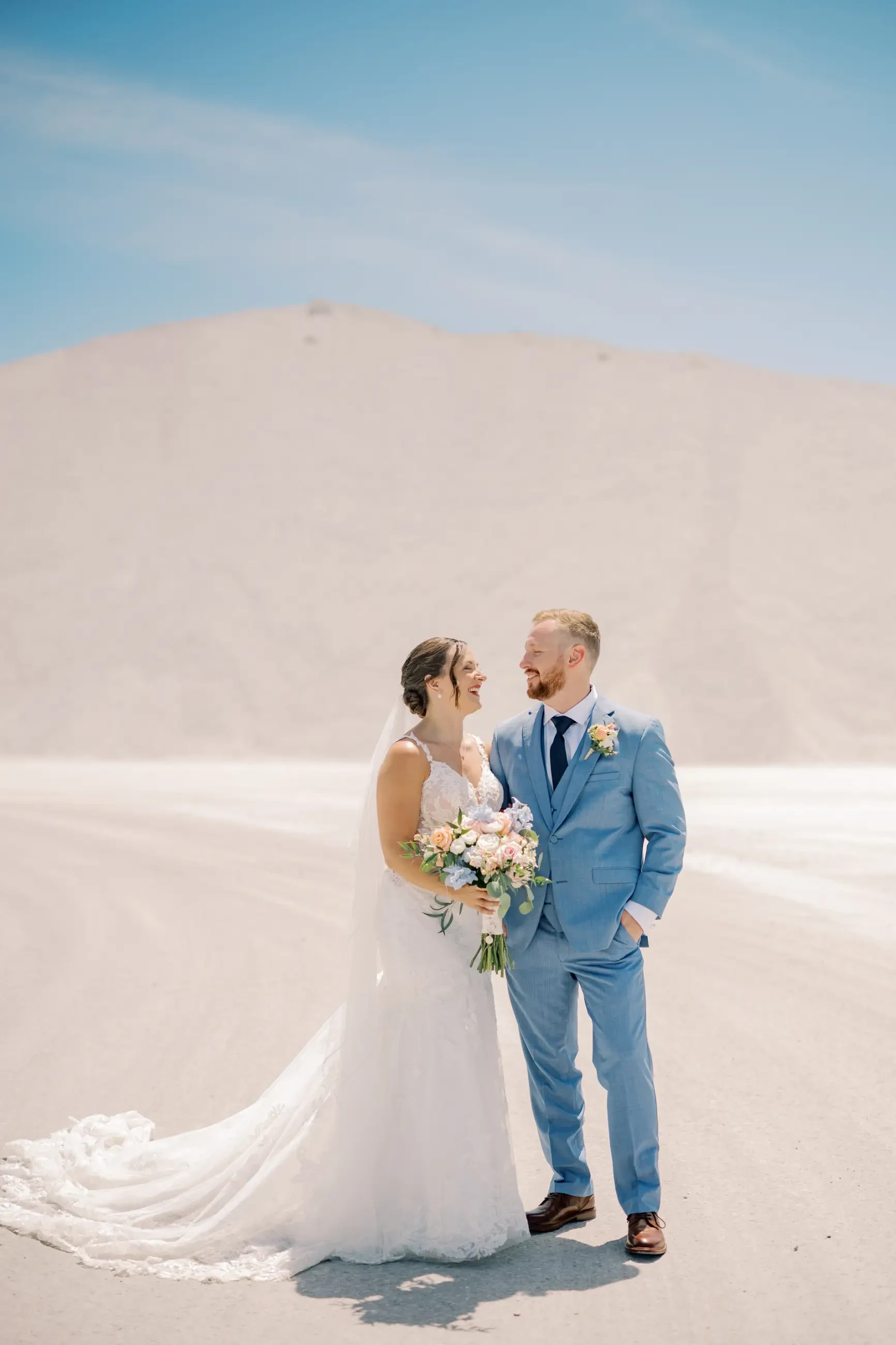 Image shows a husband and wife smiling at each other on their wedding day