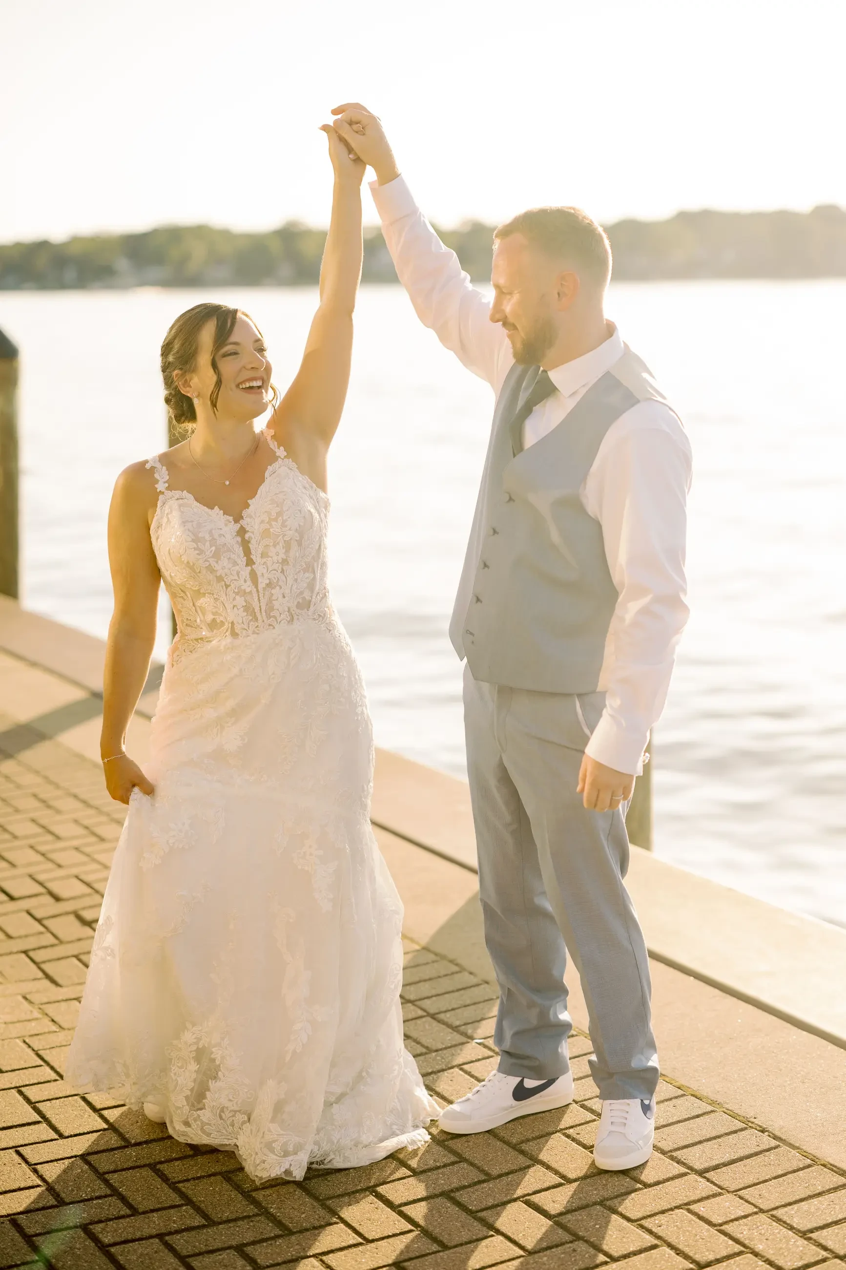Image shows a husband and wife smiling and holding hands up in the air on their wedding day