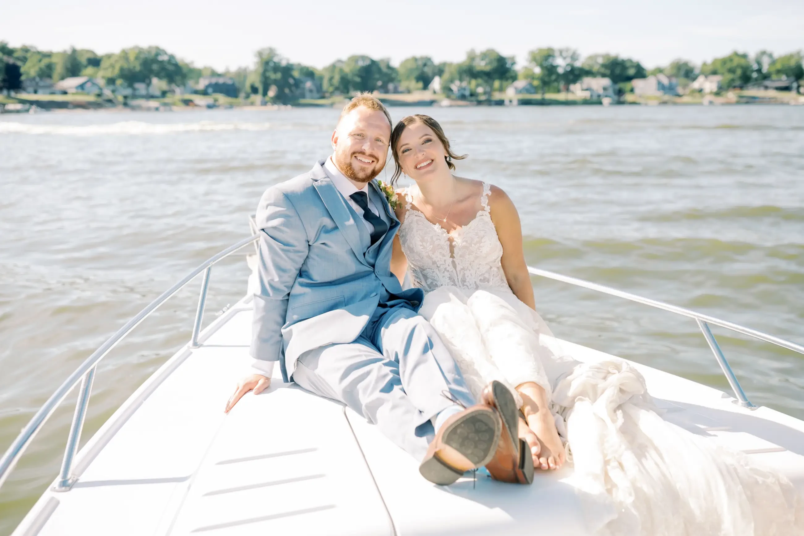 Image shows a husband and wife posing and smiling on a boat on their wedding day