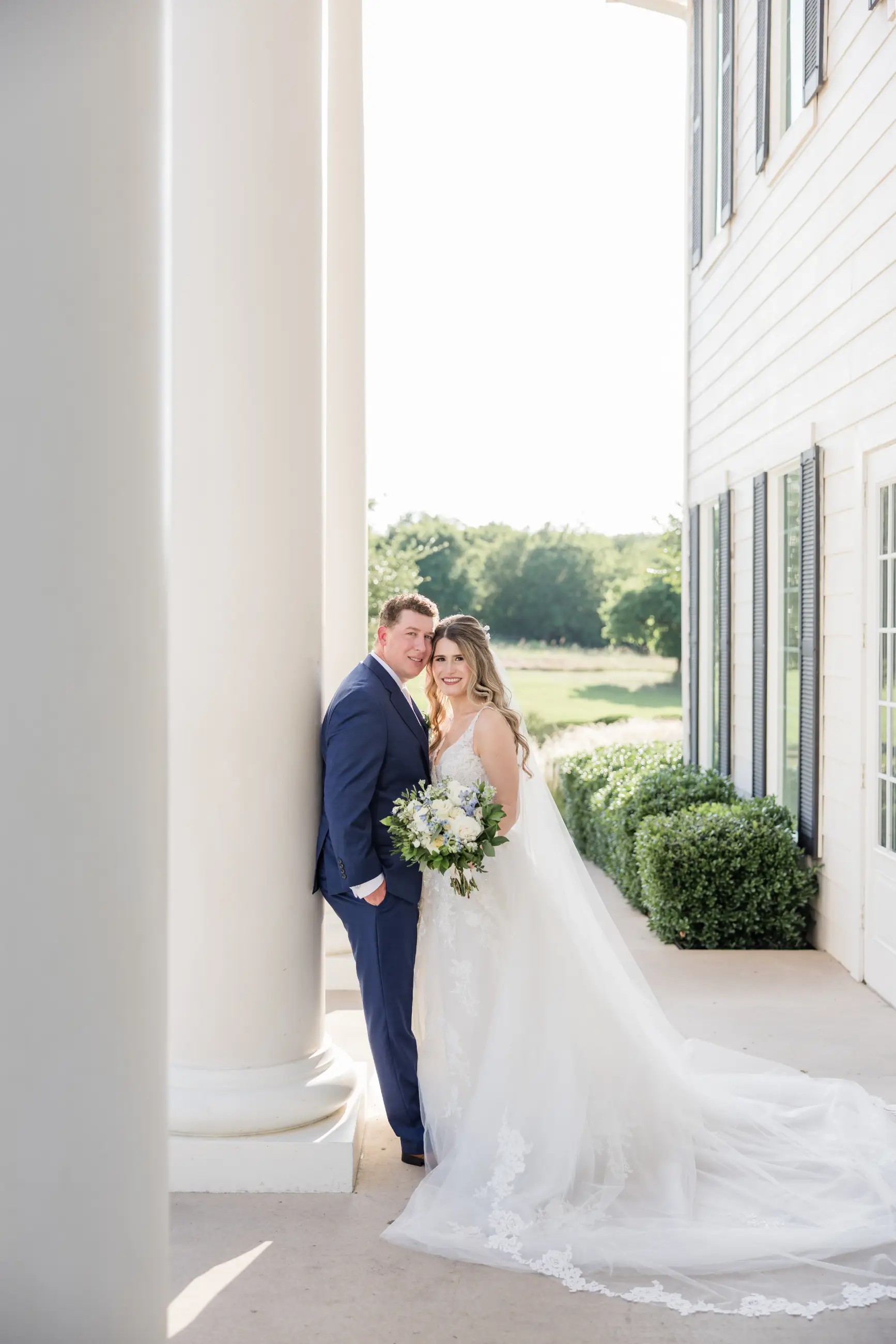 image shows a wife and her husband smiling and posing for wedding day photos 