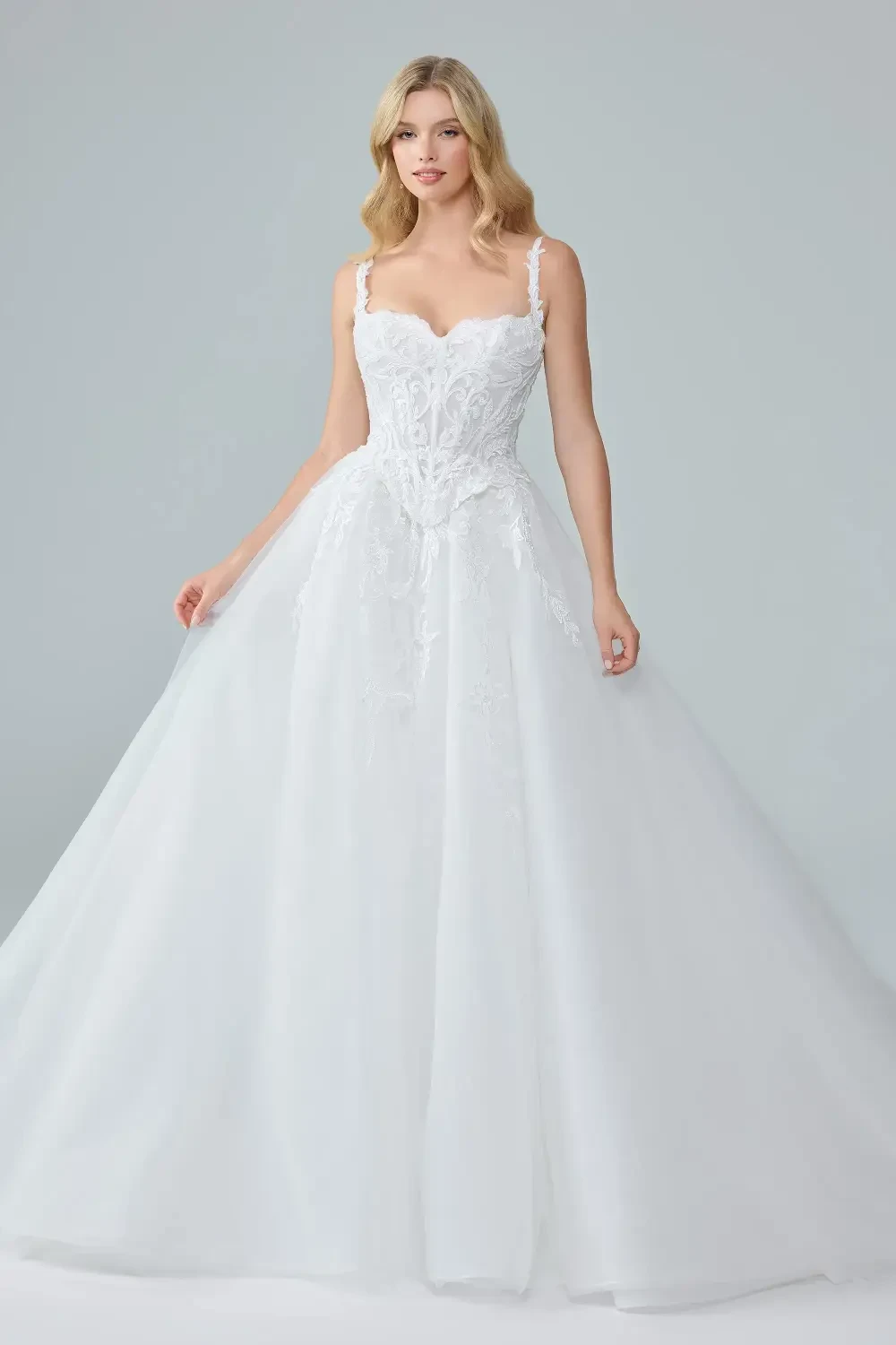 A woman wearing a beautiful white wedding dress with intricate lace detailing and a flowing skirt.