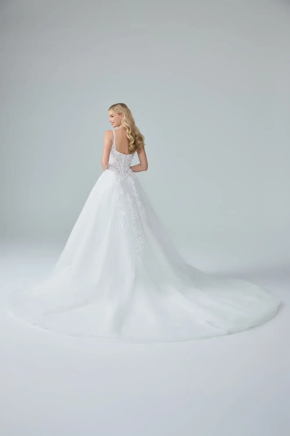 A woman wearing a beautiful white wedding dress with intricate lace detailing and a flowing skirt.